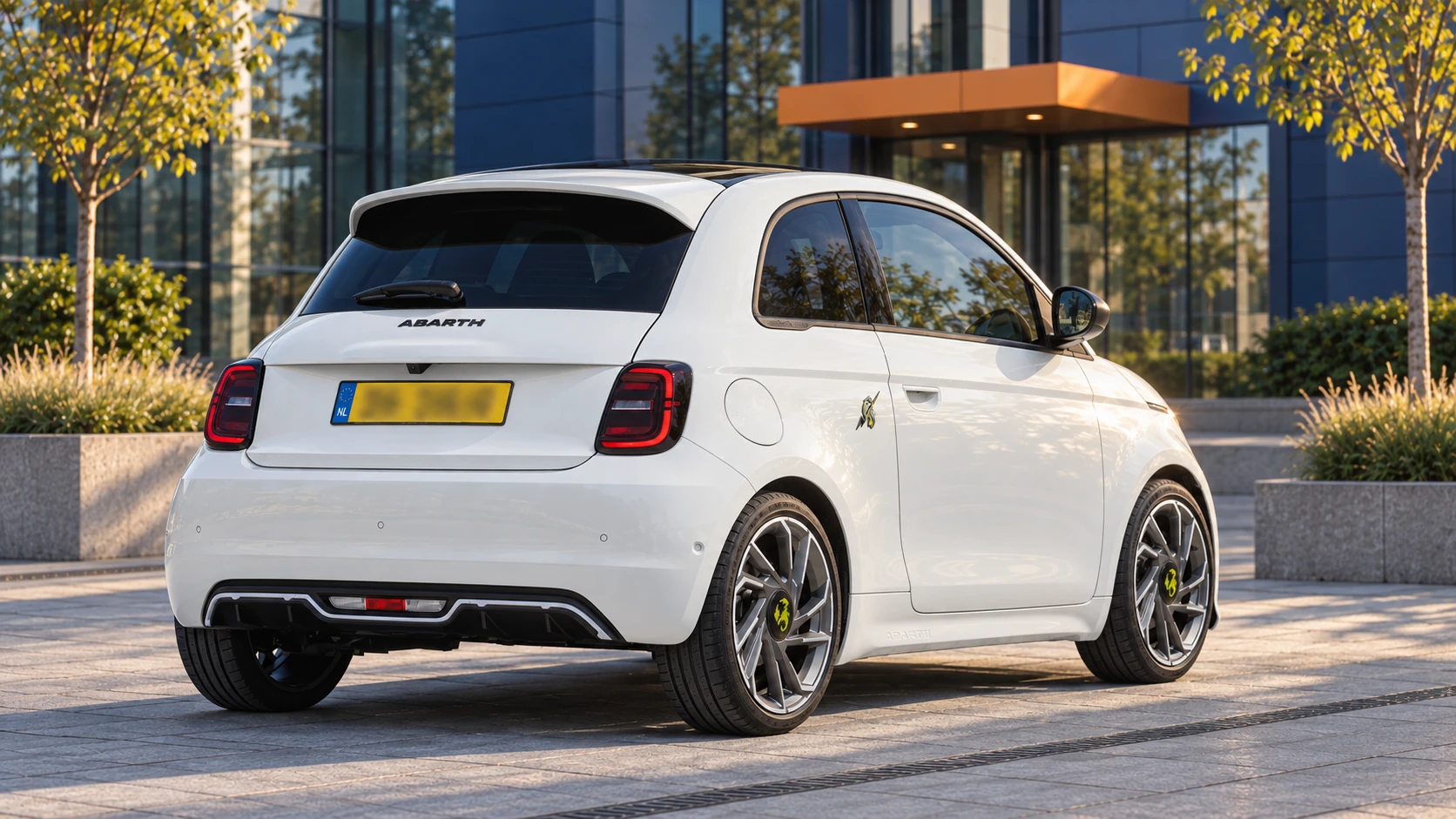 Witte Abarth 500e Turismo hatchback, schuin van achteren met de gesloten elektrische achterbumper