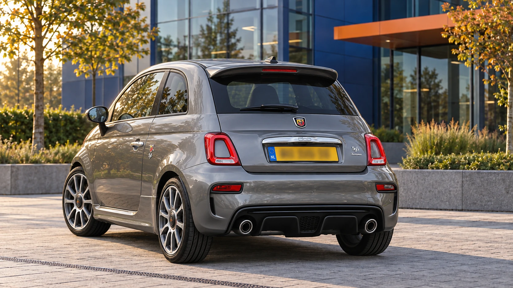 Grijze Abarth 595 hatchback, schuin van achteren gezien met gesloten dak en sportieve achterbumper