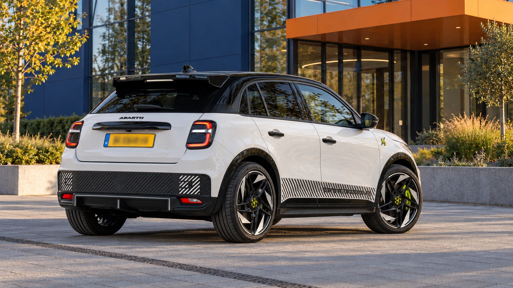 Witte Abarth 600e Competizione vijfdeurs met zwart dak, schuin van achteren met sportieve dakspoiler