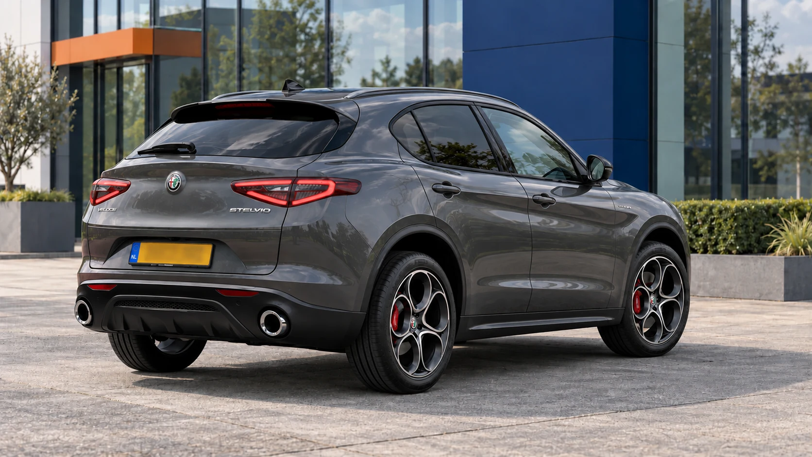 Grijze Alfa Romeo Stelvio Veloce met heldere achterlampbeglazing van de facelift, schuin van achteren