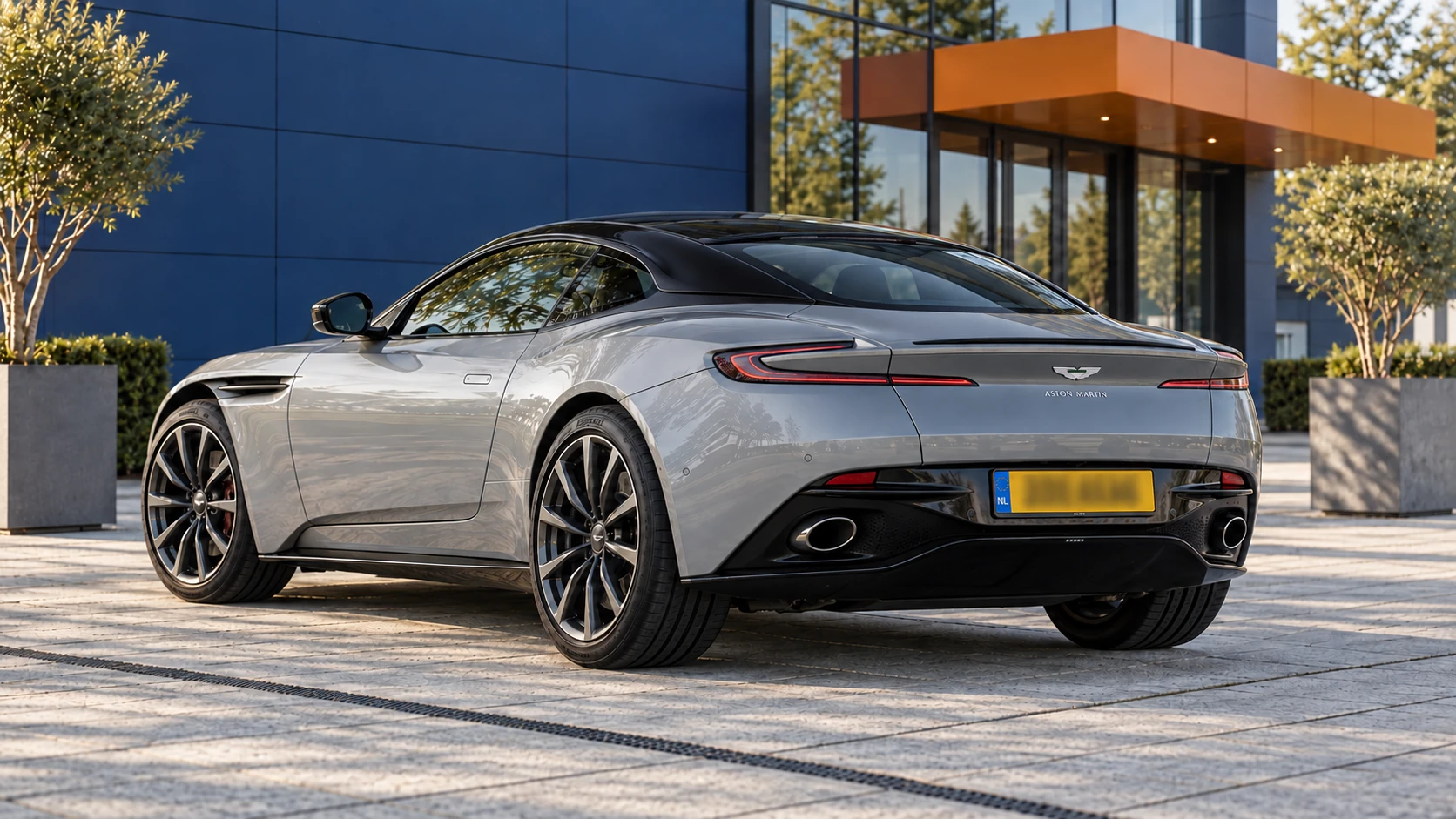 Grijze Aston Martin DB11 V8 Coupé van achteren met gesloten dak en kenmerkende smalle achterlichten