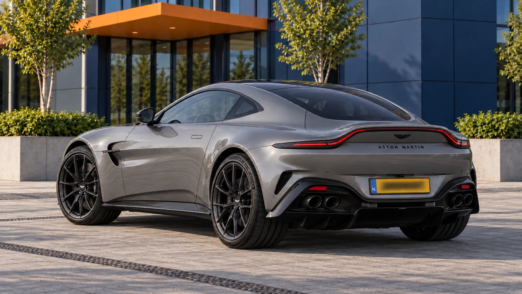 Grijze vernieuwde Aston Martin Vantage V8 Coupé van achteren met doorlopend achterlicht en vier ronde uitlaten