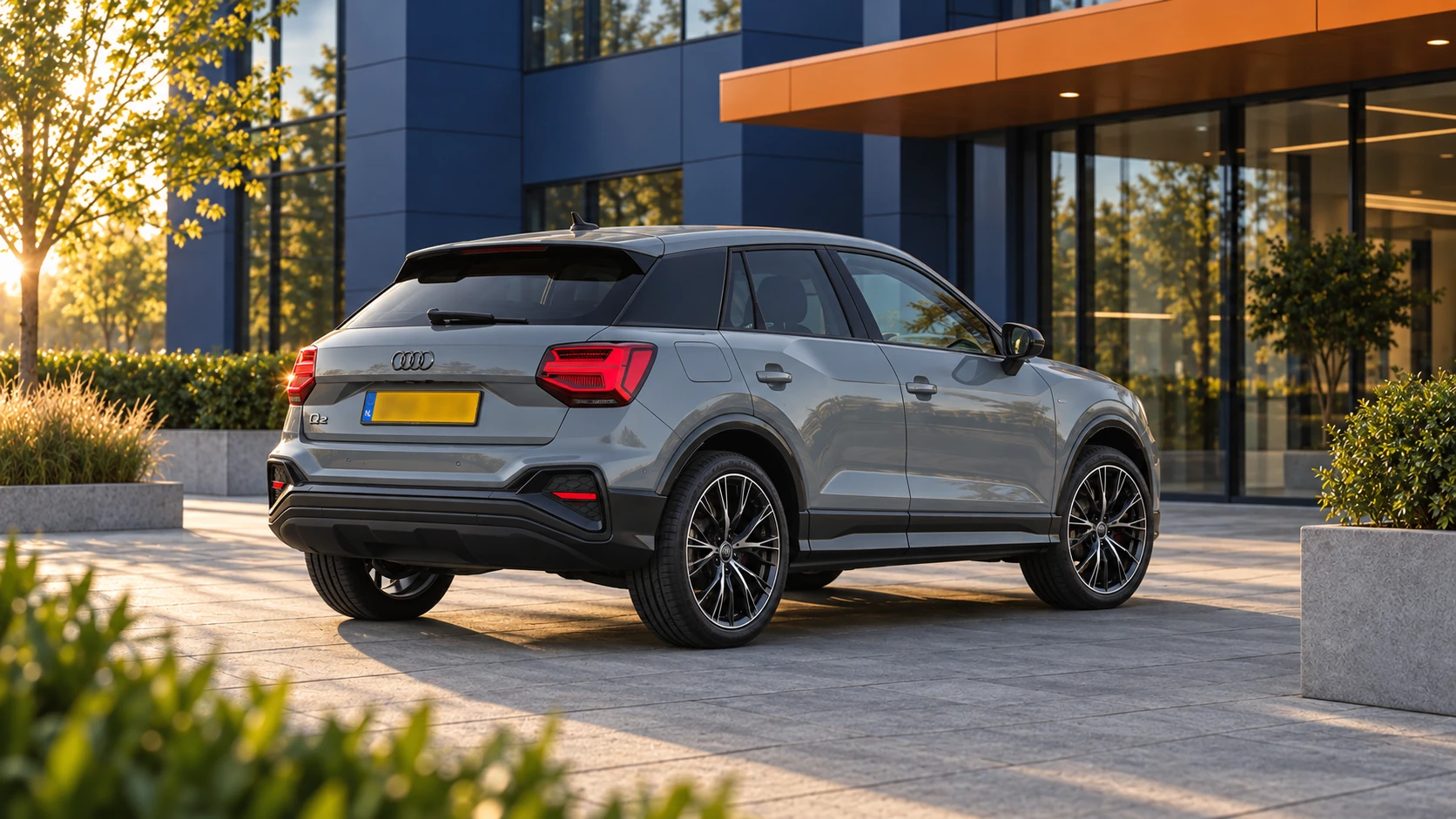 Achterzijde van een grijze Audi Q2 met afzonderlijke achterlichten en de karakteristieke C-stijlblades