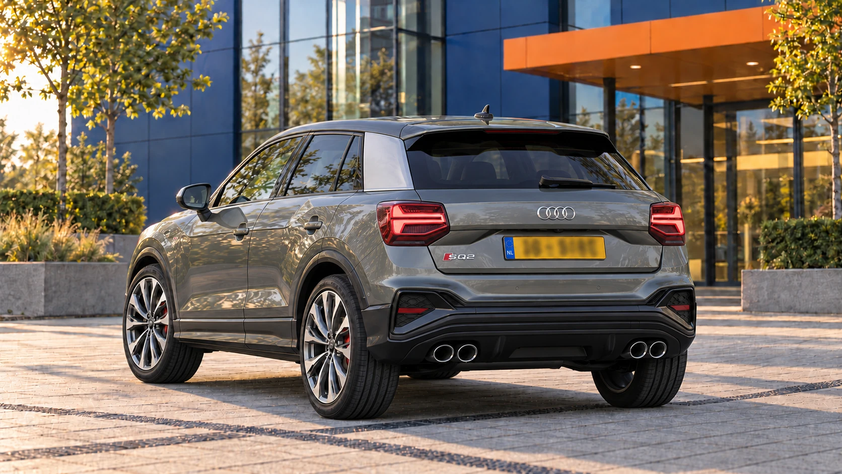 Grijze Audi SQ2 facelift vanaf 2021, schuin van achteren gezien met vier ronde uitlaten