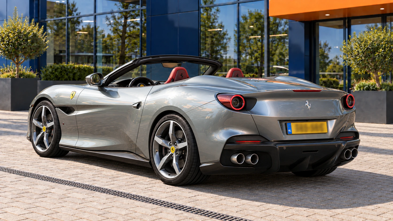 Achterzijde van dezelfde zilvergrijze Ferrari Portofino M met geopend dak