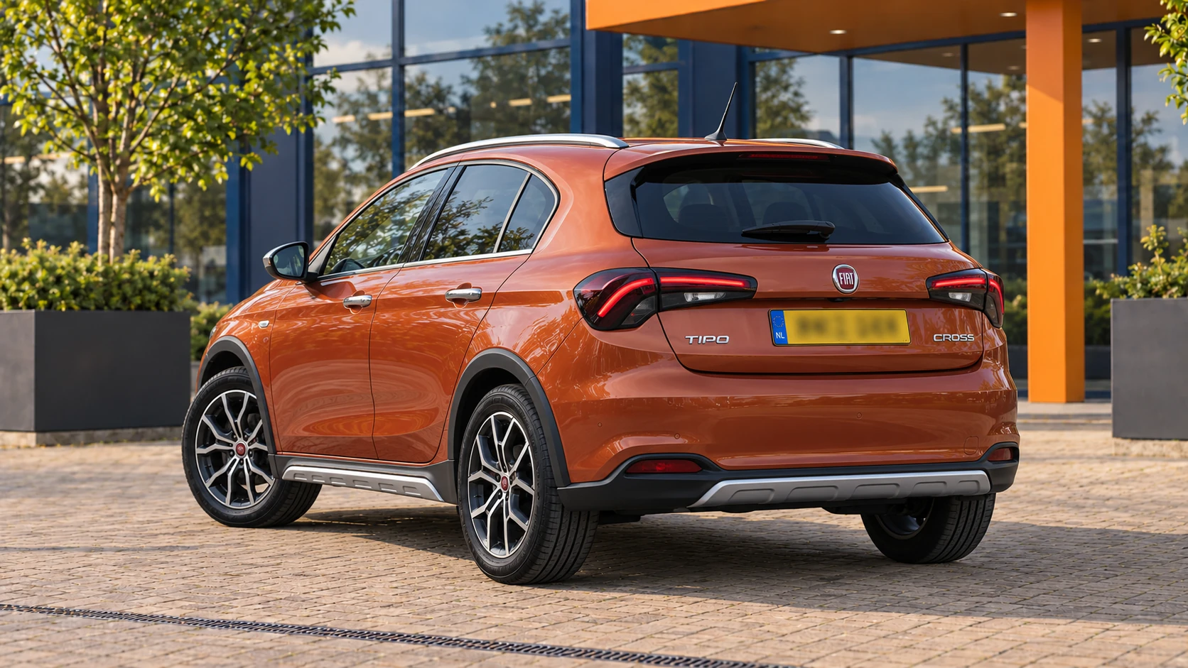 Achterzijde van dezelfde oranje vijfdeurs Fiat Tipo Cross