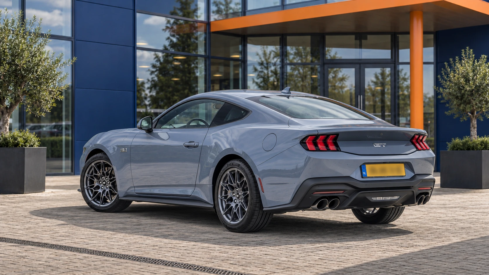 Achterzijde van dezelfde grijsblauwe Ford Mustang GT Fastback