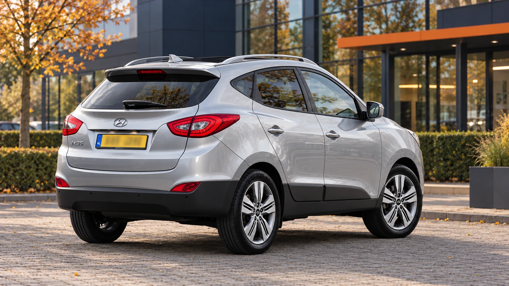 Dezelfde zilvergrijze Hyundai ix35 van de facelift uit 2013, schuin van achteren