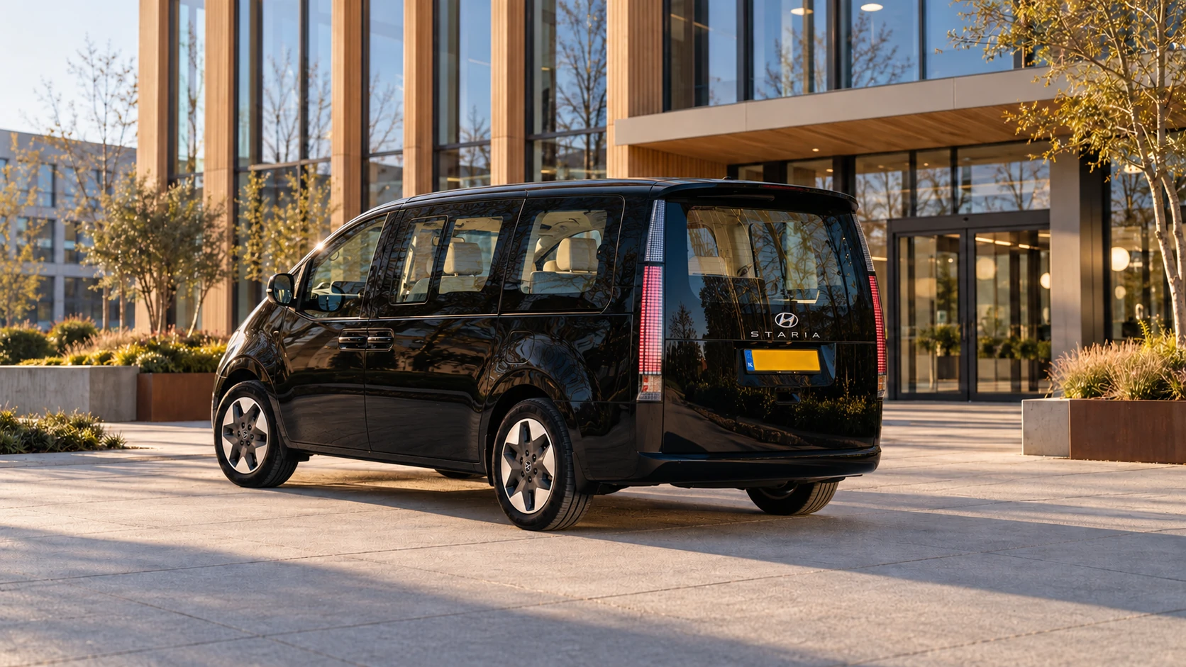 Dezelfde zwarte Hyundai Staria personenbus, schuin van achteren