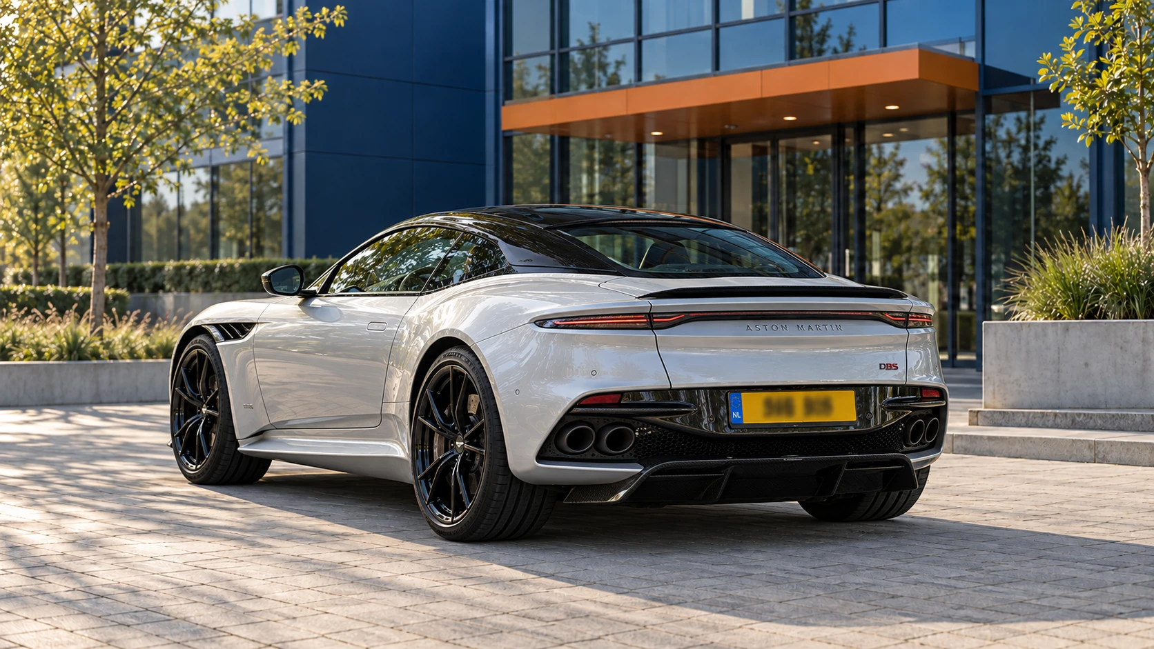 Achterzijde van een zilveren Aston Martin DBS Superleggera Coupé met vier uitlaatpijpen
