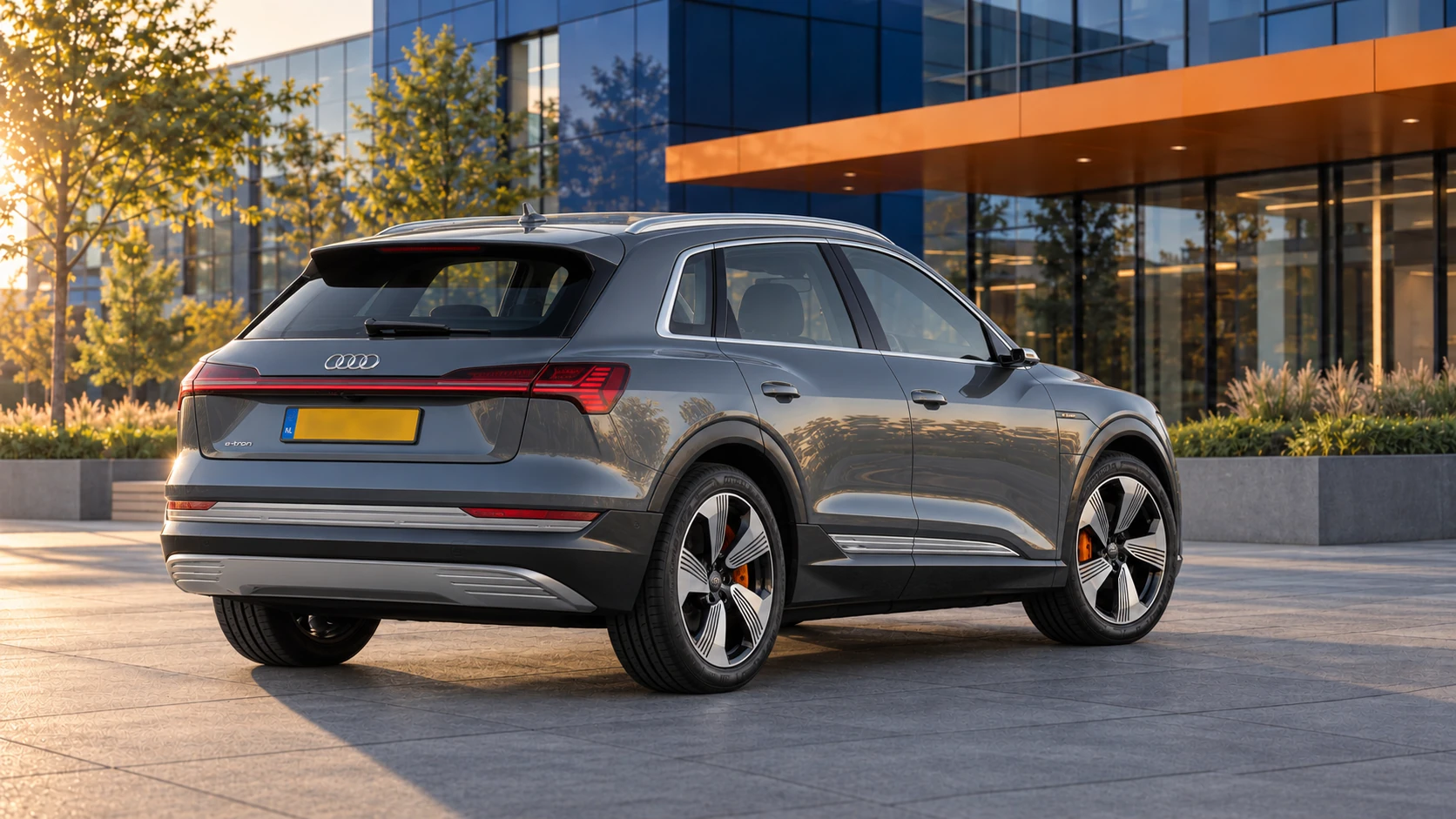 Grijze oorspronkelijke Audi e-tron van vóór de Q8-vernieuwing, gewone elektrische SUV schuin van achteren
