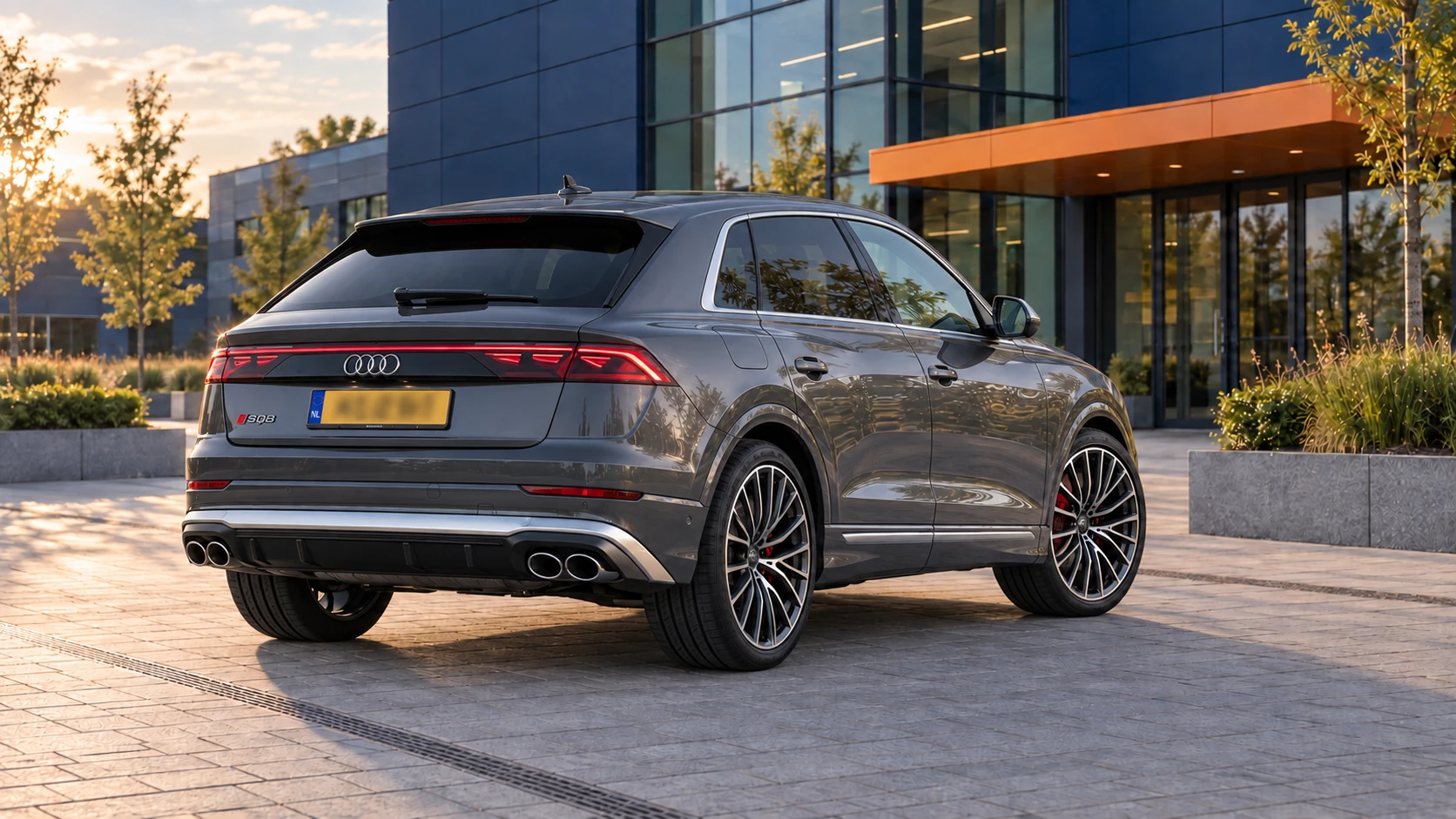 Grijze Audi SQ8 TFSI van de eerste generatie na de facelift van 2023, schuin van achteren met de SUV-coupédaklijn