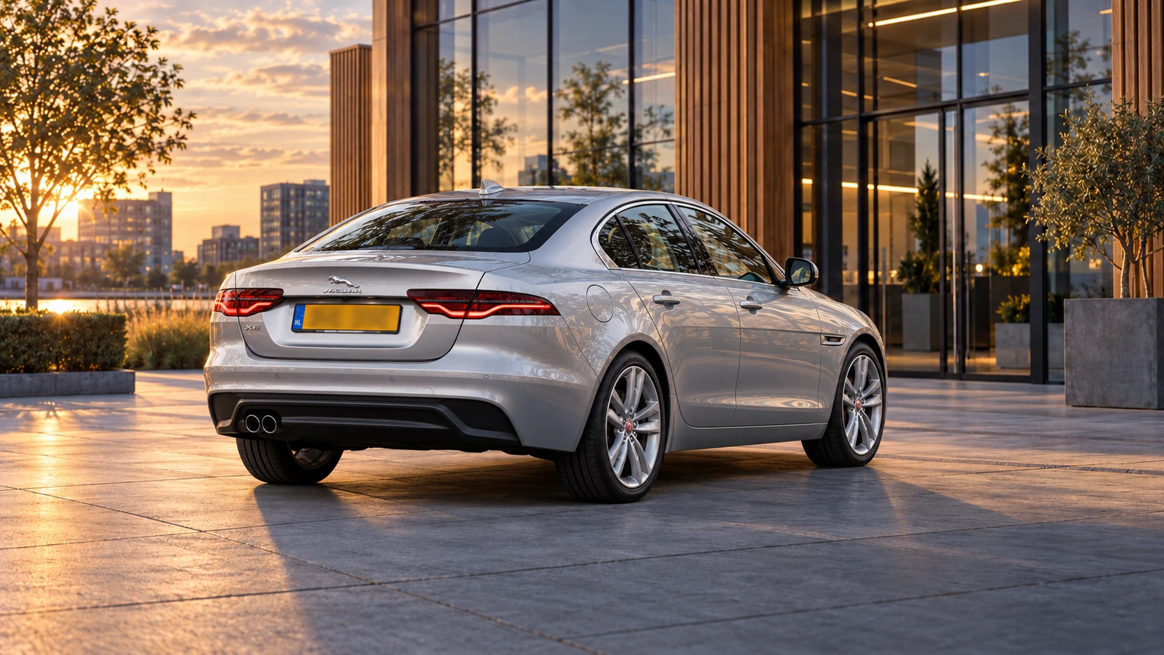 Dezelfde zilvergrijze Jaguar XE sedan, schuin van achteren