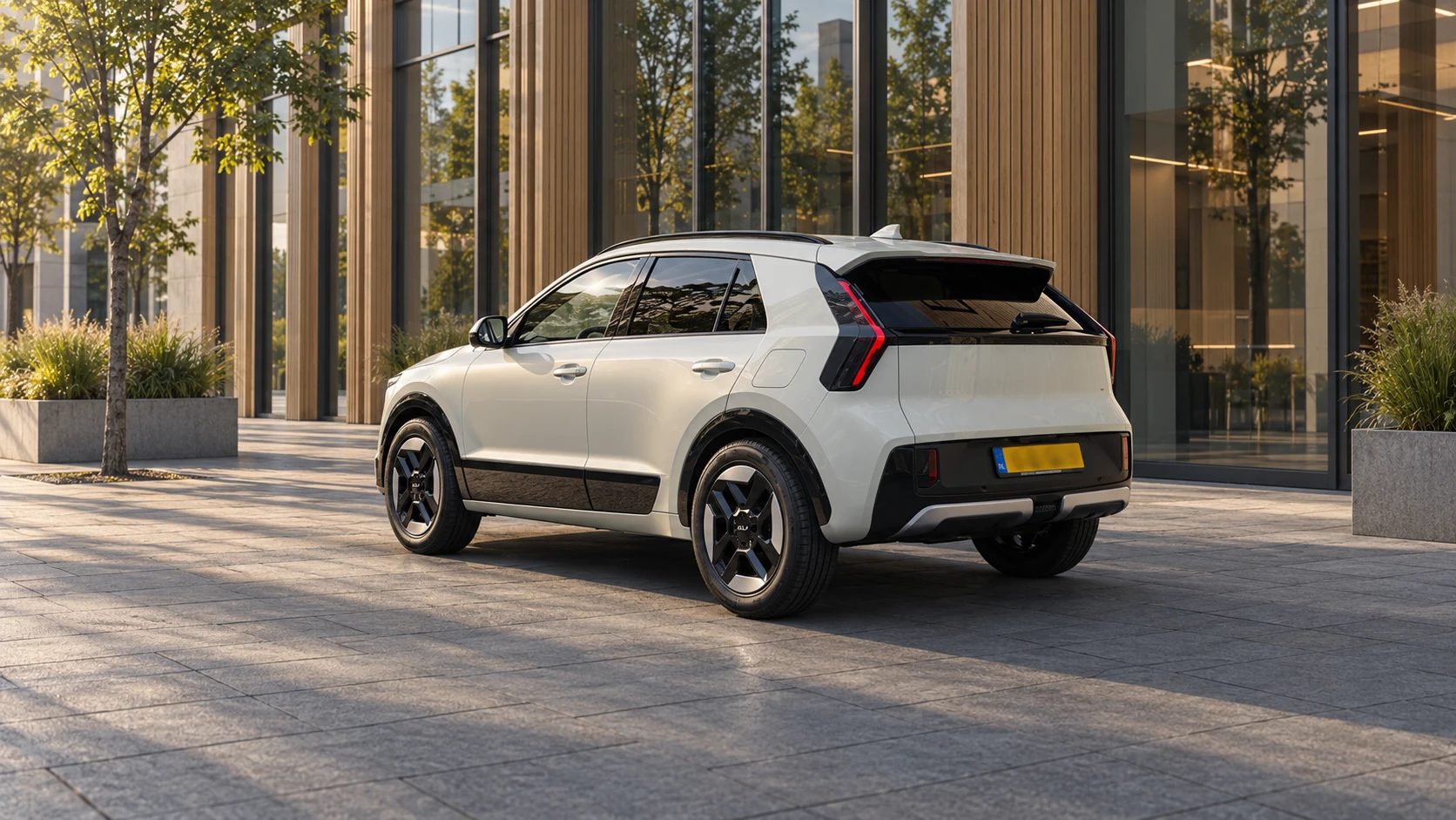 Dezelfde witte Kia Niro crossover, schuin van achteren